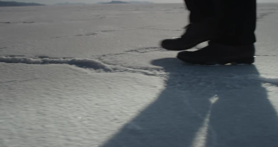 A man walks across salt flats on a sunny day