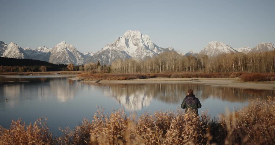 Person takes pictures of a lake and mountains