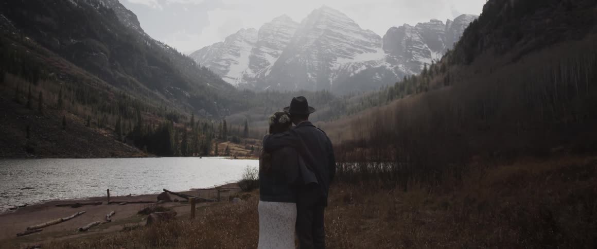 A man is taking photographs of a lake before a mountain