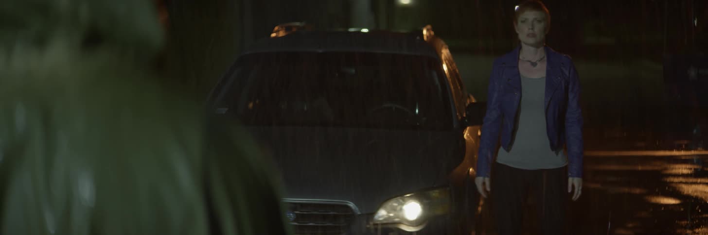 Woman gets out of car on a rainy night and faces another person