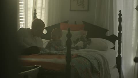 Man plays with a baby on a bed