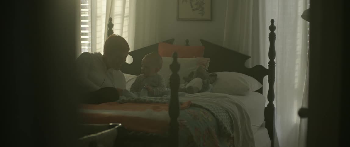 Man plays with a baby on a bed