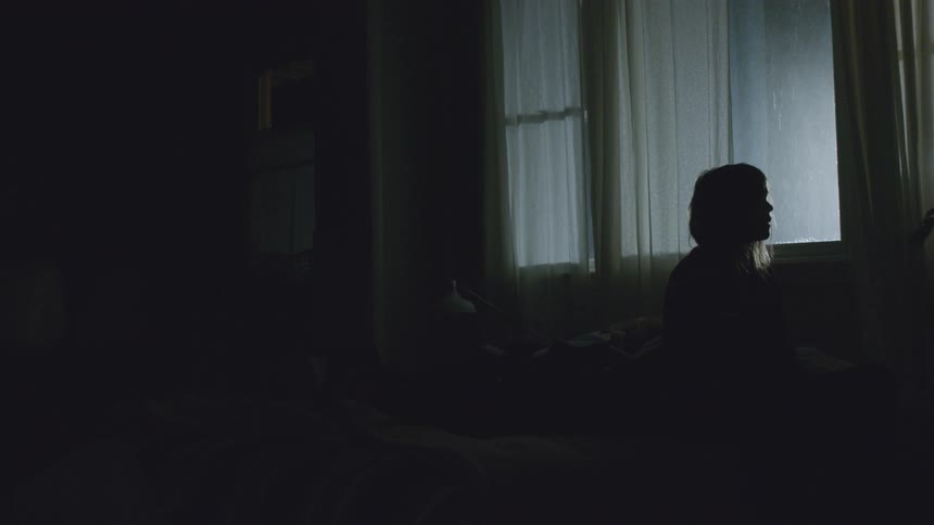 Silhouette of a woman sitting next to a window on a stormy night