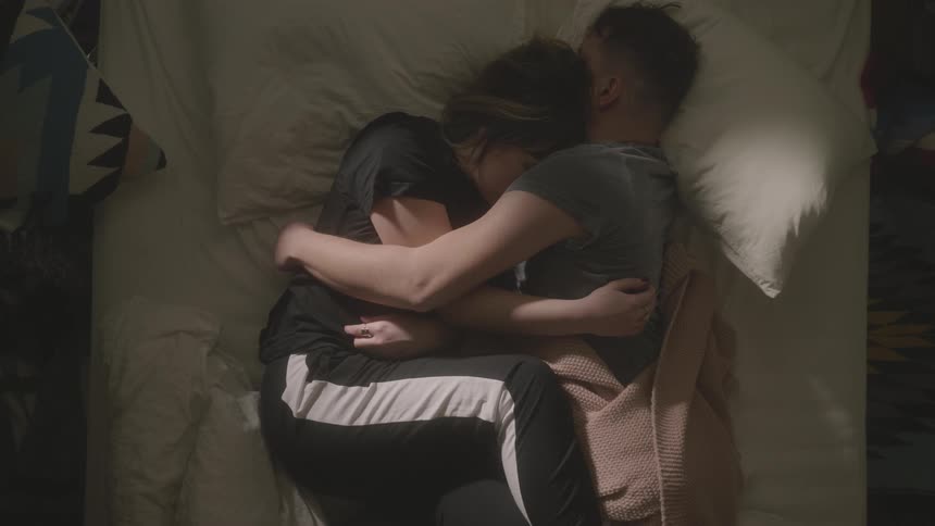 A man and woman snuggle in bed