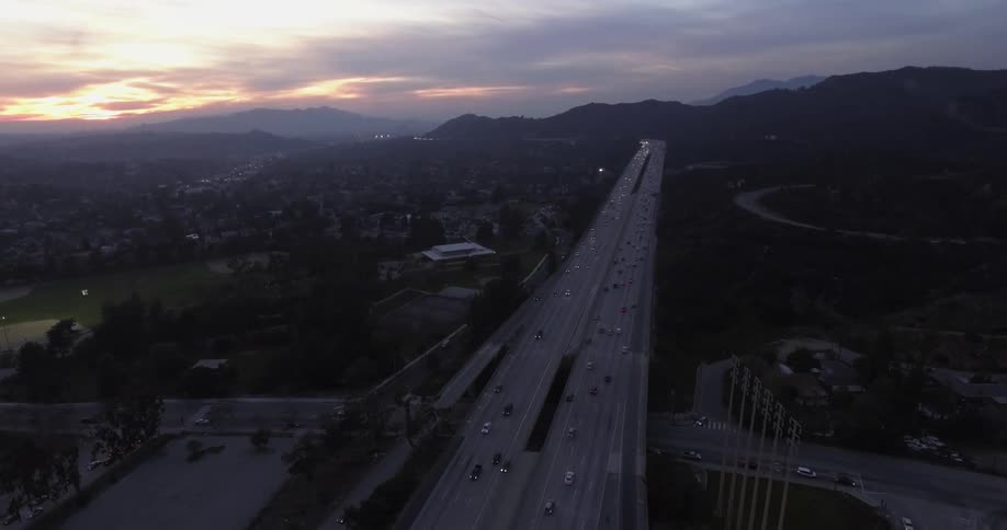 Cars speed down a highway next to a city