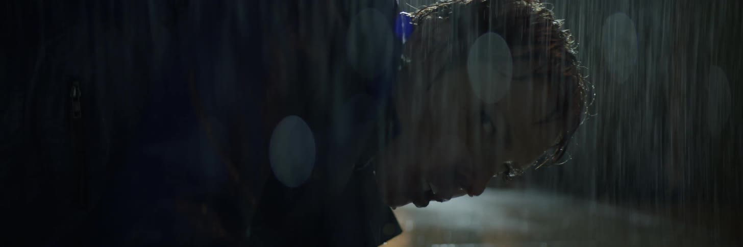 A woman falls to the ground in the rain and looks over her shoulder