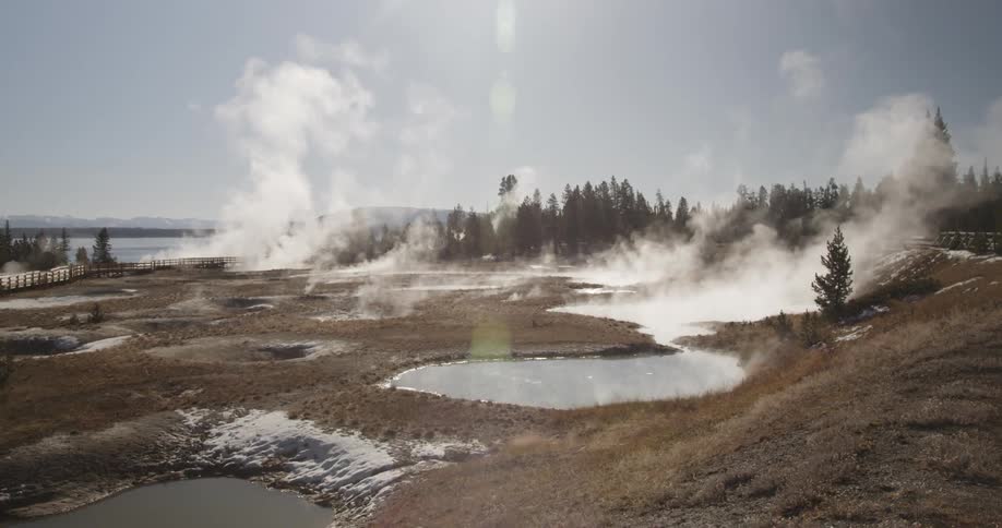 Steam rises from hot springs on a sunny day