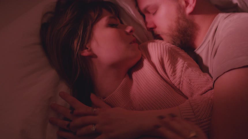 A man and woman lay in bed together and talk