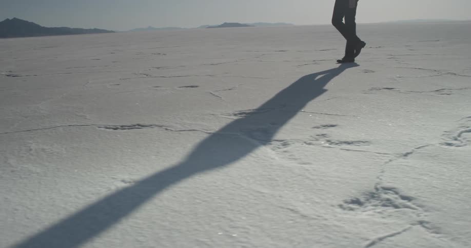 A man walks across salt flats on a sunny day
