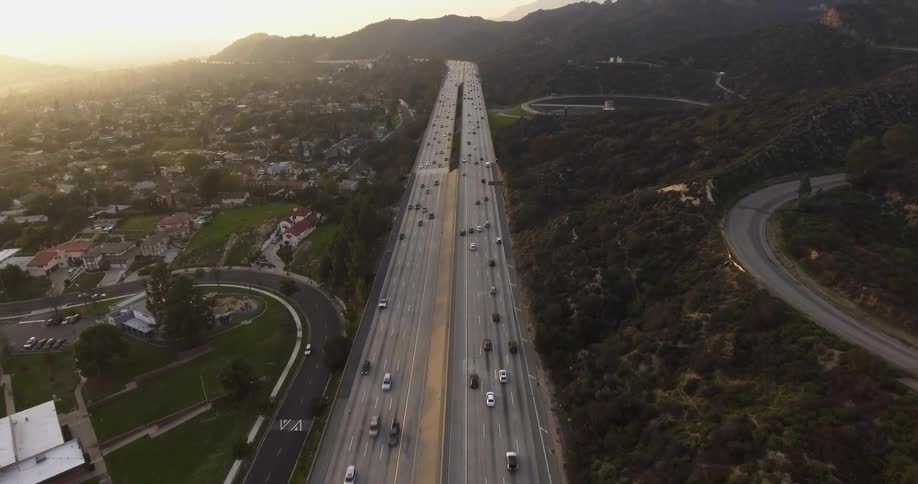 Cars drive on a city highway at sunset