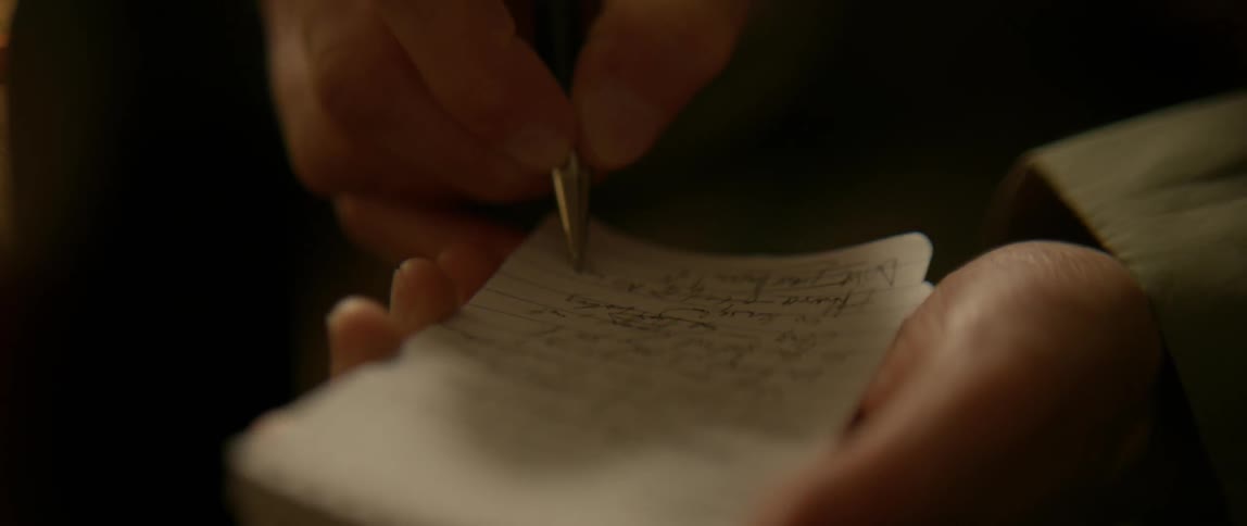 A person writes in a small notepad with a pen