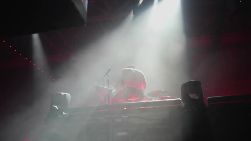 A man is performing on stage with drums