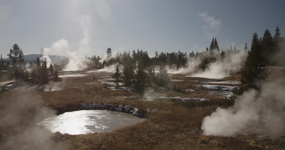 Steam rises from hot springs on a sunny day