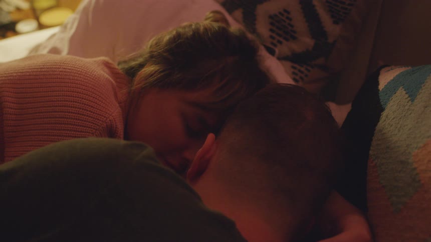 A man and woman cuddle while laying in bed