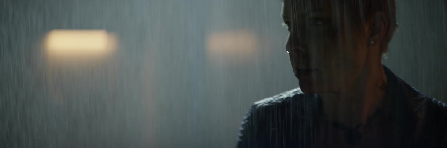 Woman stands up and looks behind her shoulder in the rain at night