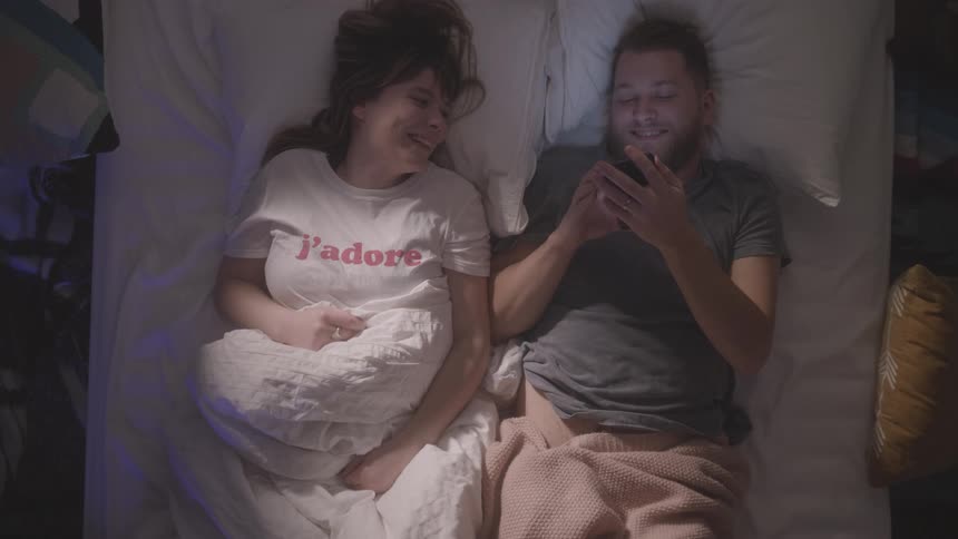 A man in woman lay in bed together talking and laughing