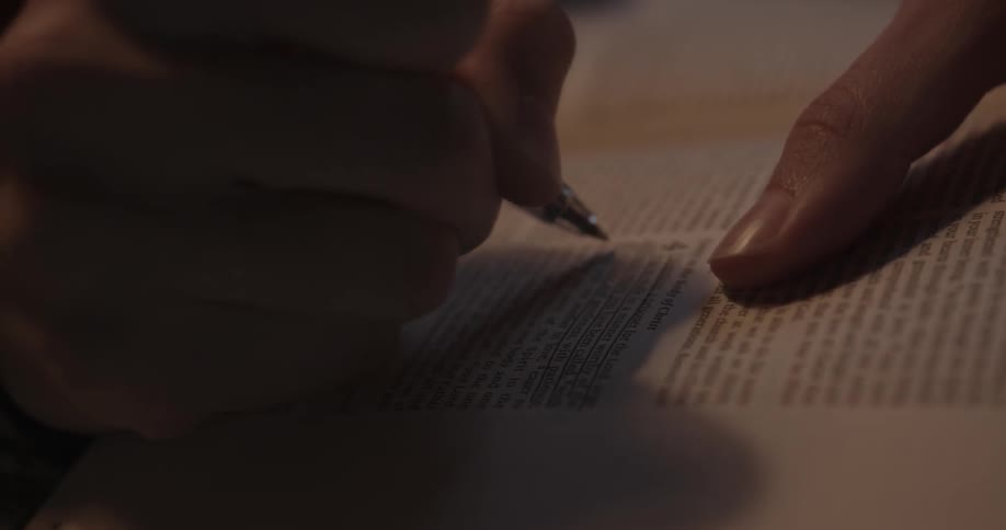 A woman underlines text in a bible with a pen
