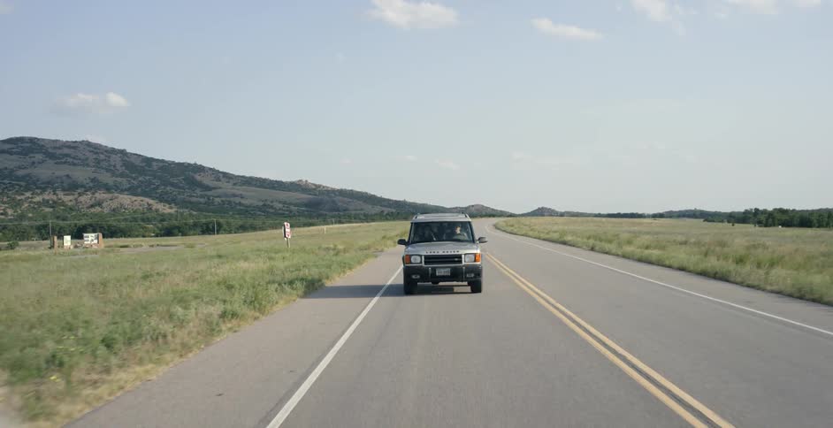 Jeep drives down a country road on a sunny day