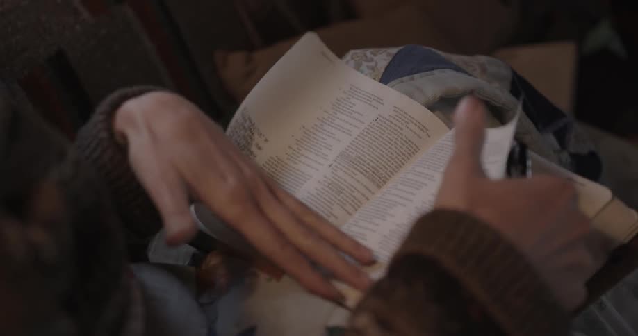 A woman flips through a bible with a pen in hand