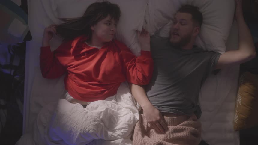 A man and woman talk while laying in bed