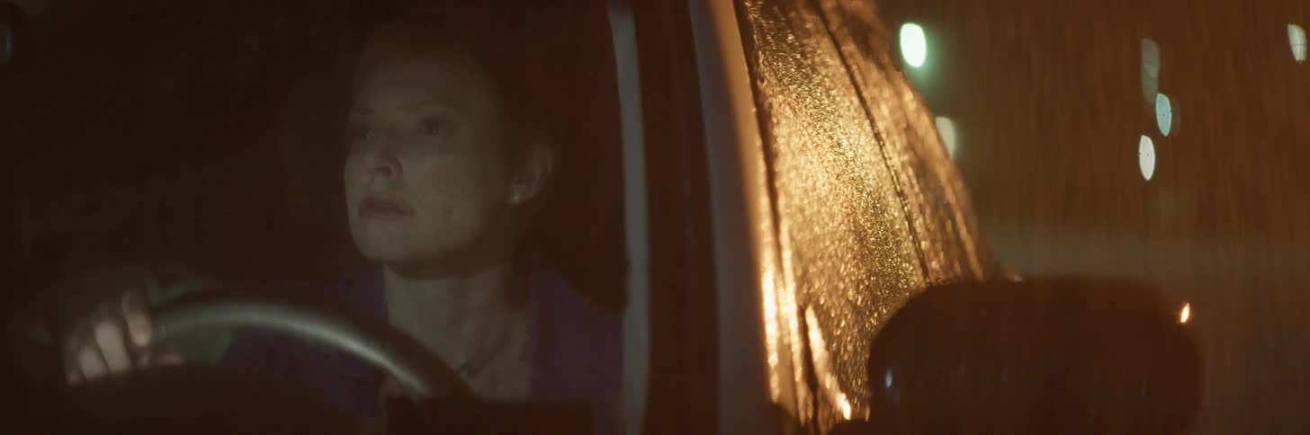 Angry looking woman sitting in a vehicle at night