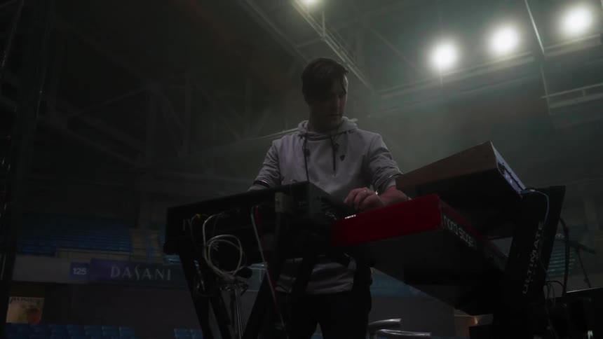A man stands next to a keyboard on stage
