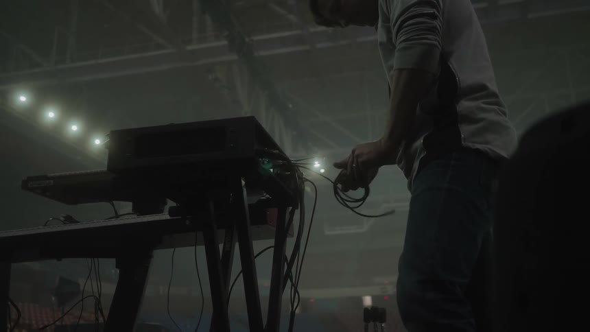 A man is unrolling a cable on a music keyboard and equipment