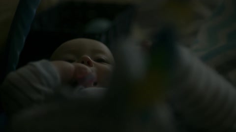 A baby laying on the floor chewing its hand