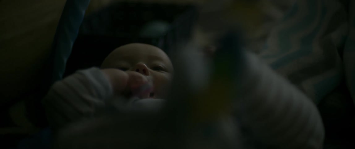 A baby laying on the floor chewing its hand