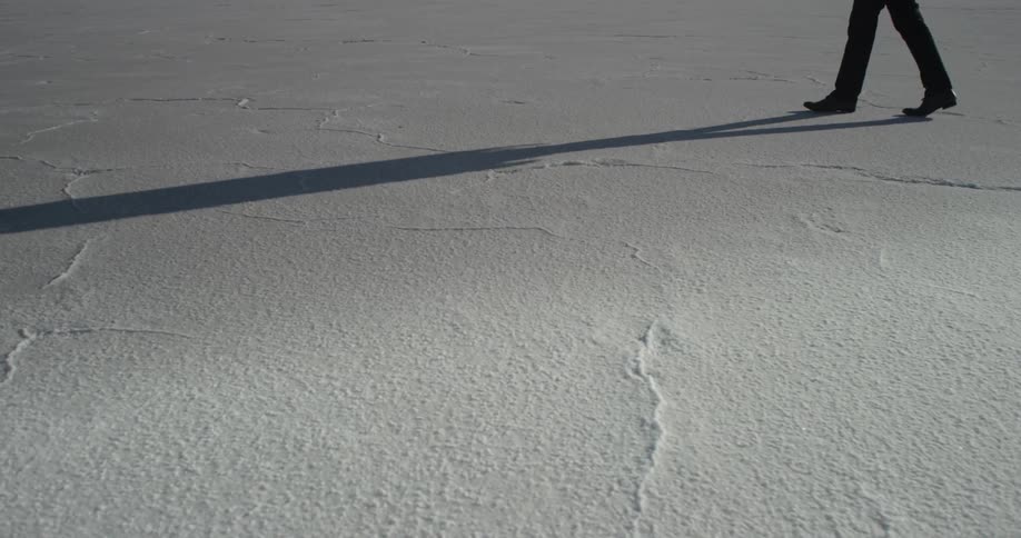 A man walks across salt flats on a sunny day