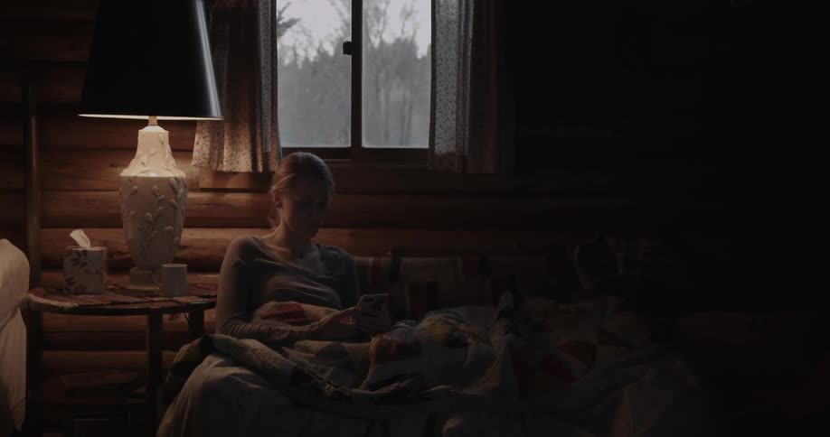 A woman is sitting by a window in the dark