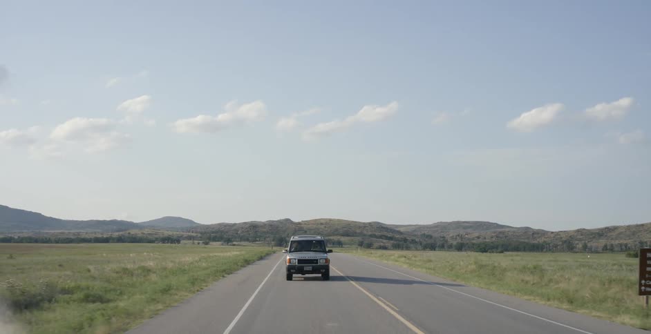 Jeep drives down a country road on a sunny day