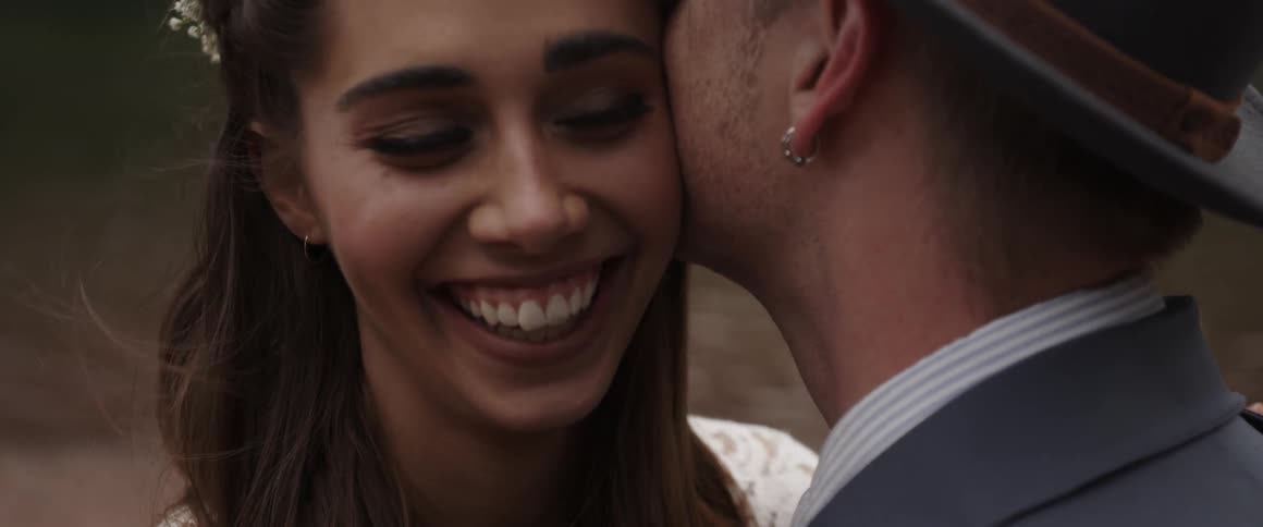 A man kisses a woman on the cheek as she smiles