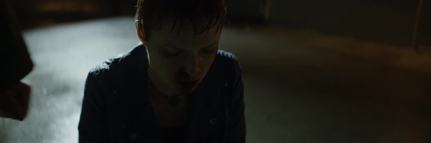A bleeding woman is circled by a man