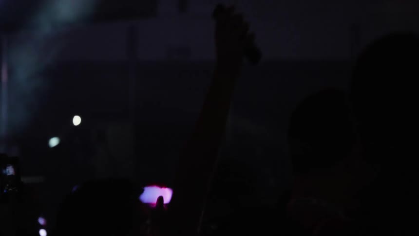 A crowd at a concert waving phones and glow sticks