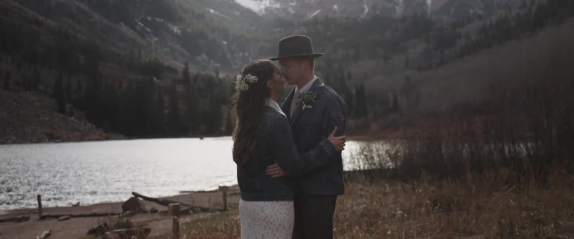 A man and woman kiss by the lake
