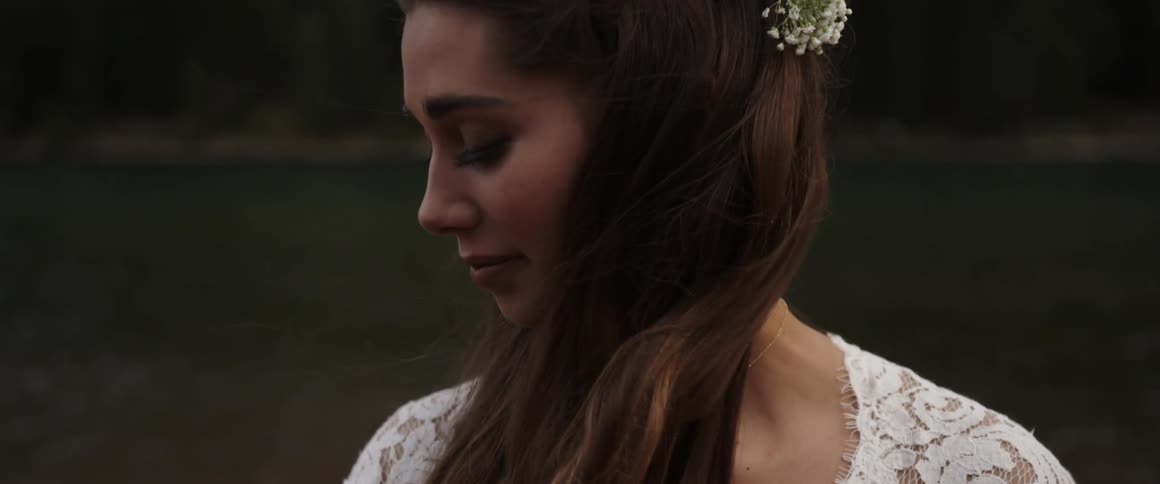 Wind blows through a bride's hair on a lakeshore