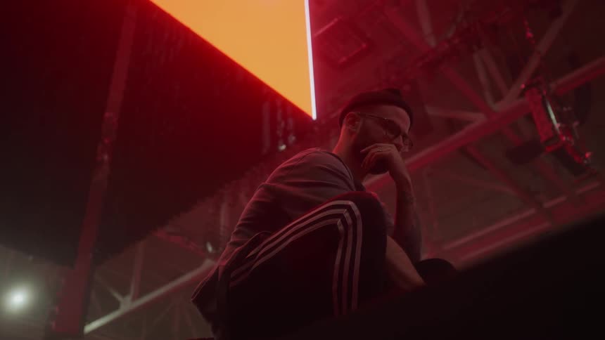 A kneeling man looks at a laptop on stage