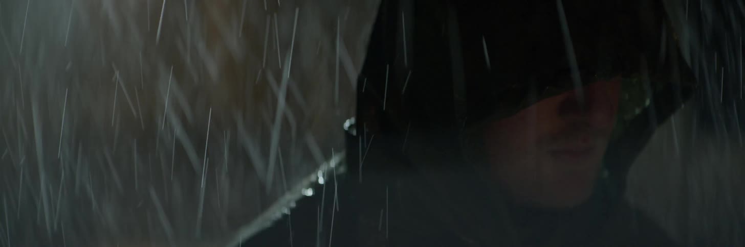 A man wears a hood while standing outside in the rain