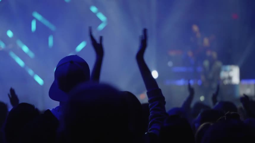 An audience claps for a band playing at a concert
