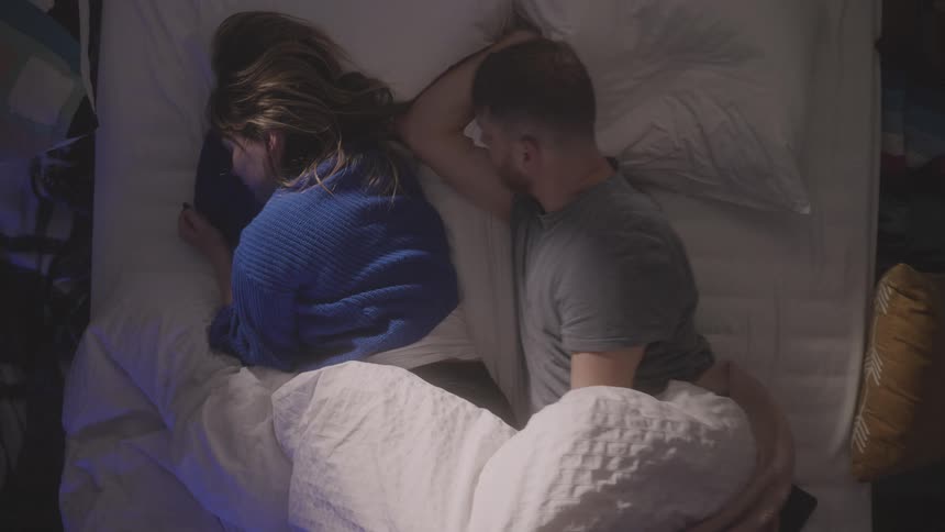 A man and woman are sleeping in bed