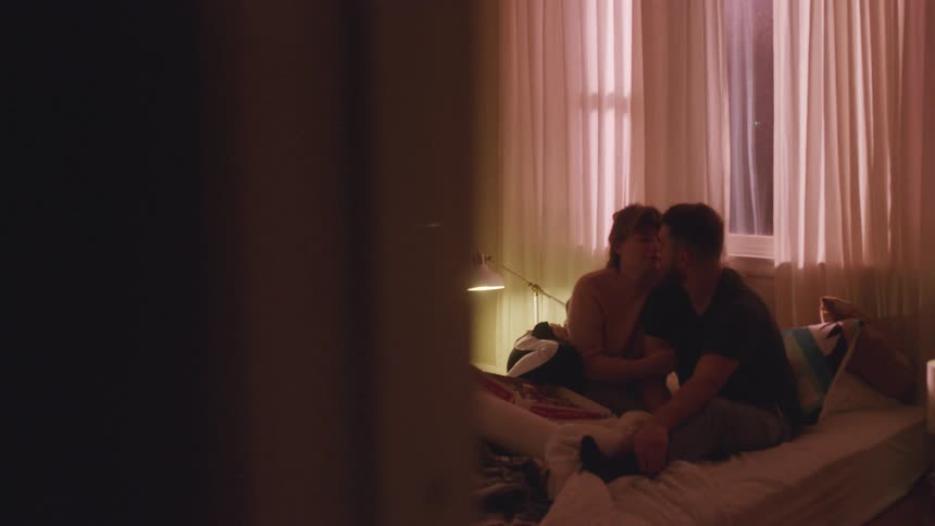 A man and woman sit in bed together