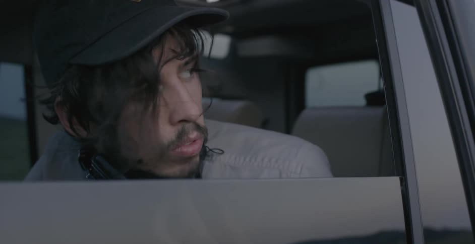 Man sitting in a vehicle wearing headphones takes them off