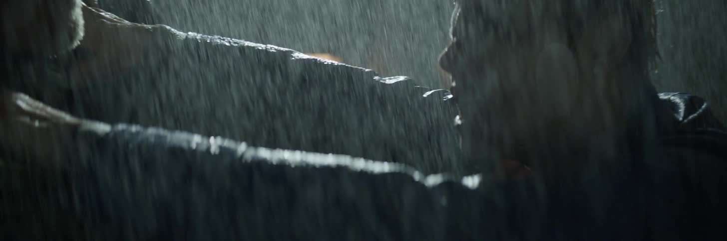Two people fight each other in the rain at night