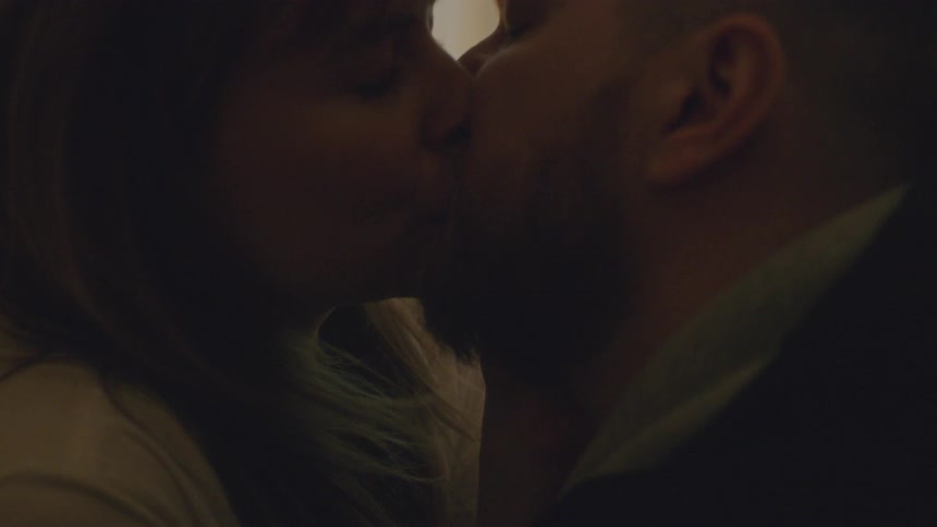A man and woman kiss while sitting in bed