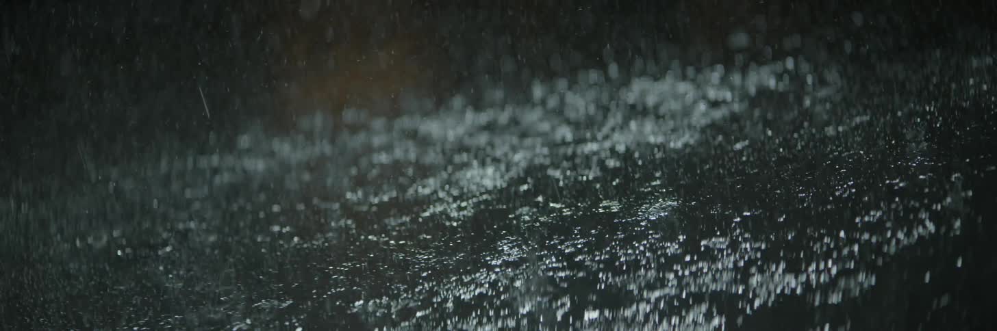 Rain splashing onto pavement at night