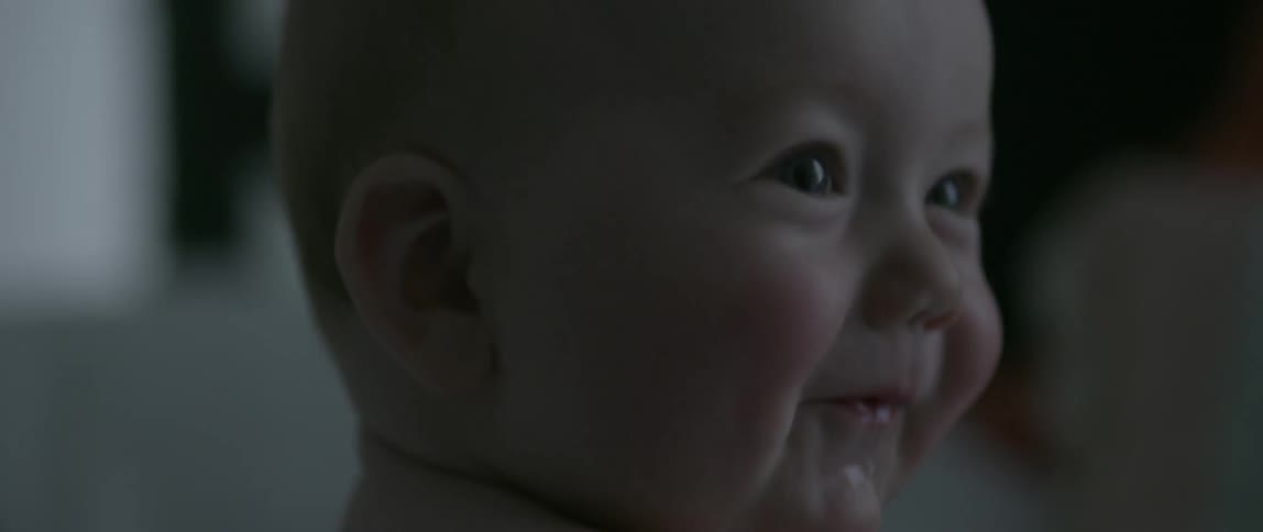 A naked baby waves its arms and smiles