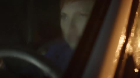 Angry looking woman sitting in a vehicle at night