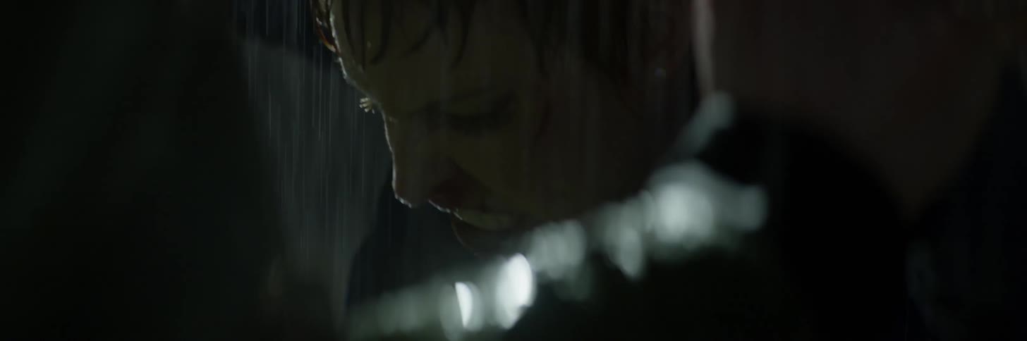 A woman is struggling against a man outside at night in the rain