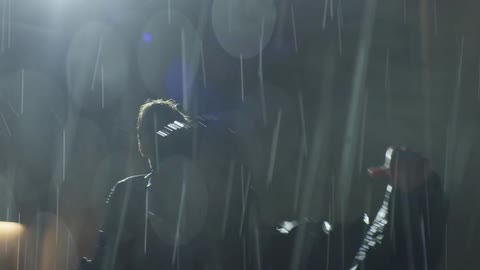 Two people fight in a parking lot in the rain